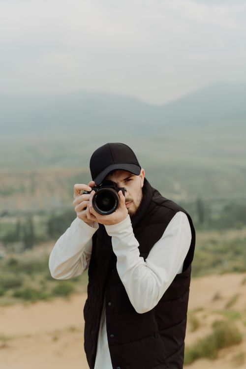 Free Outdoor shot of a male photographer taking landscapes with a DSLR. Stock Photo