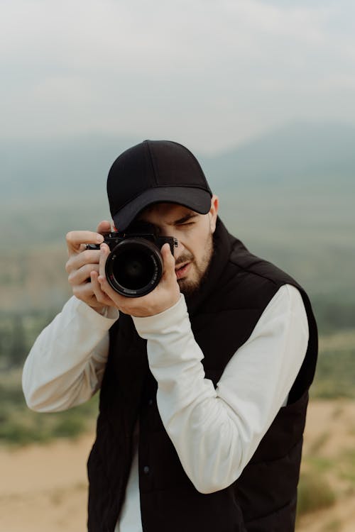 Man Wearing Black Cap Taking Photo with a Camera
