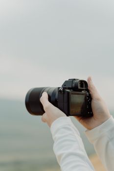 Hands holding a digital camera outdoors. Ideal for photography themes.