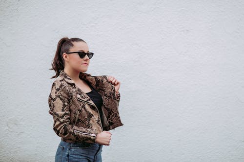Foto Wanita Mengenakan Jaket Kulit Ular Coklat Hitam Di Samping Dinding