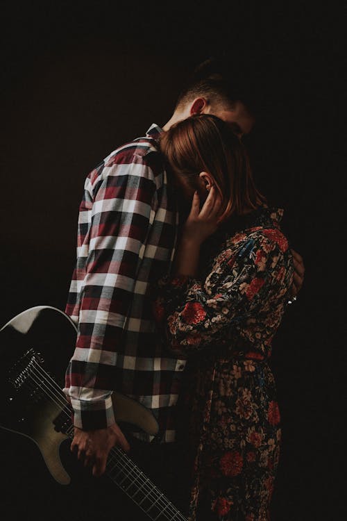 A Man Hugging a Woman while Holding an Electric Guitar
