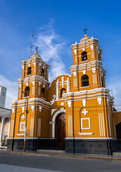 A vibrant yellow colonial-style church with white detailing stands under a clear blue sky.