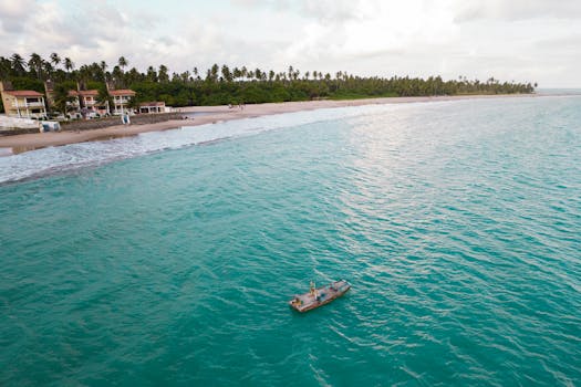 Aerial view of a wooden boat floating on turquoise waters along a pristine Brazilian coastline.