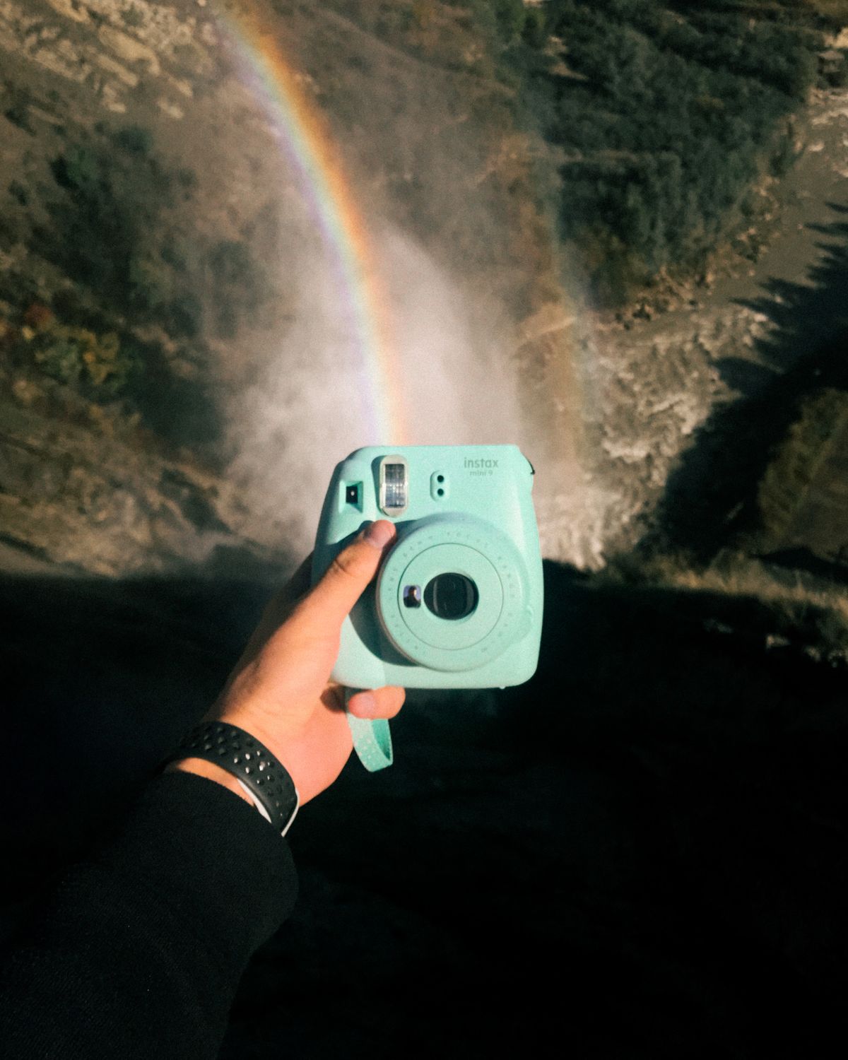 Hand holding a pastel instant camera ready for photo booth portraits