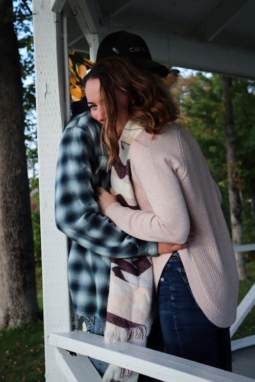 Woman in Gray Sweater Hugging a Man in Plaid Shirt