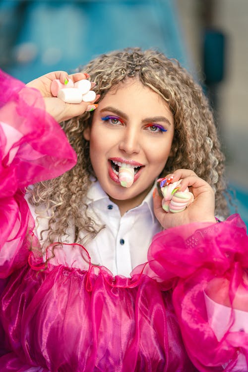 A Woman Eating Marshmallow while Smiling at the Camera