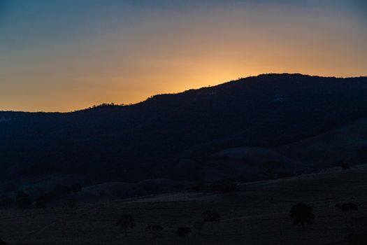 A tranquil sunset scene over silhouette of hills, capturing the beauty of nature's golden hour.