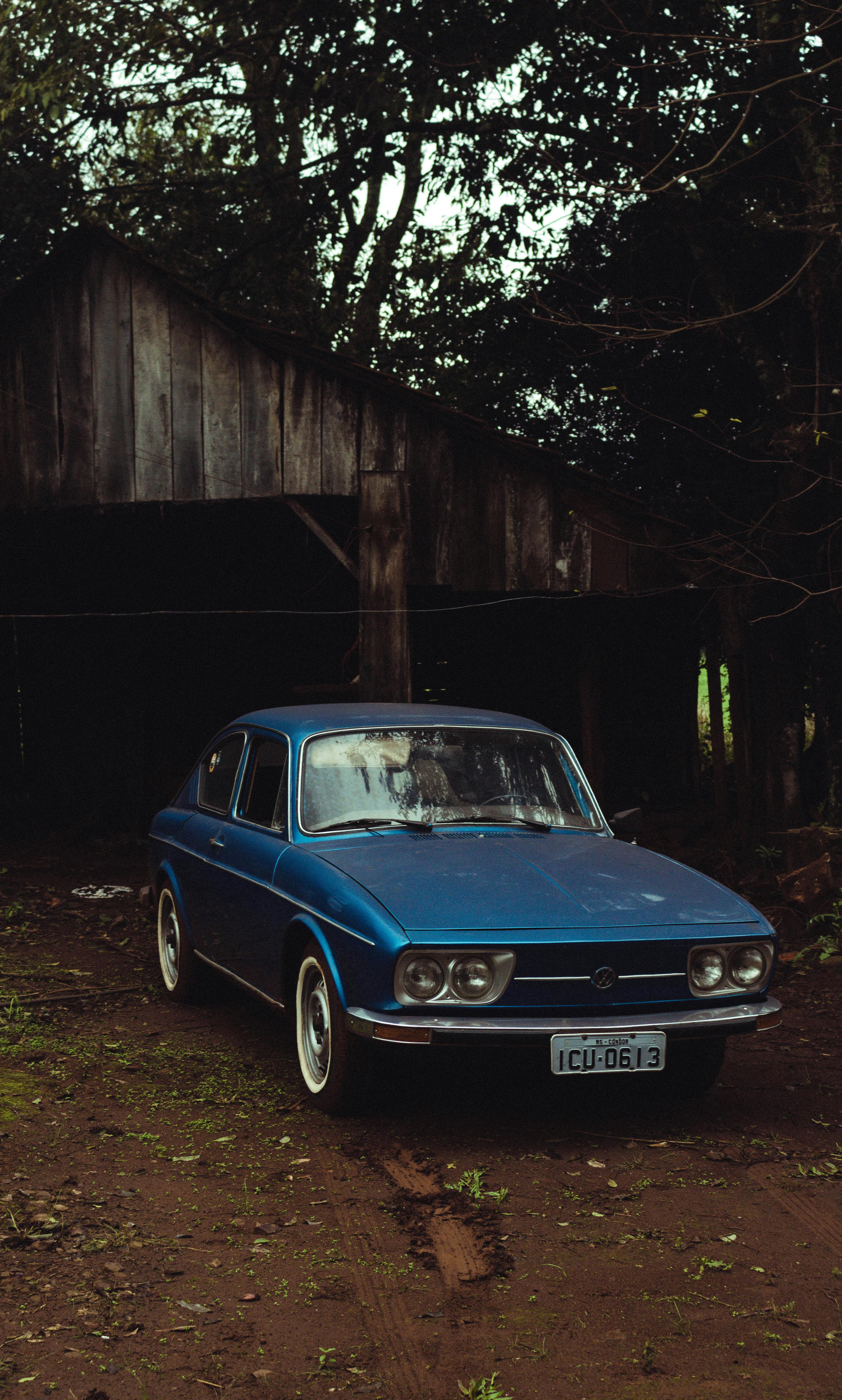 A Vintage Car Parked Near a Wooden House · Free Stock Photo