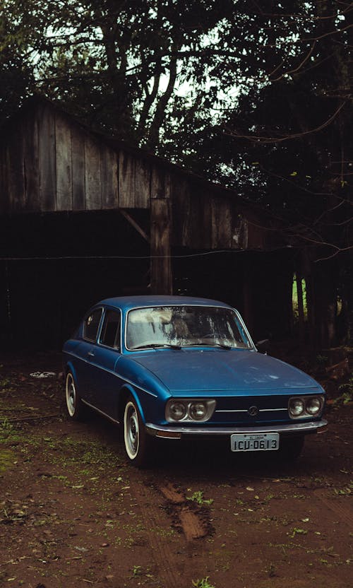Free A Vintage Car Parked Near a Wooden House Stock Photo