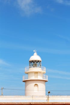 Scenic view of a lighthouse in Alicante, Spain with vibrant blue sky.