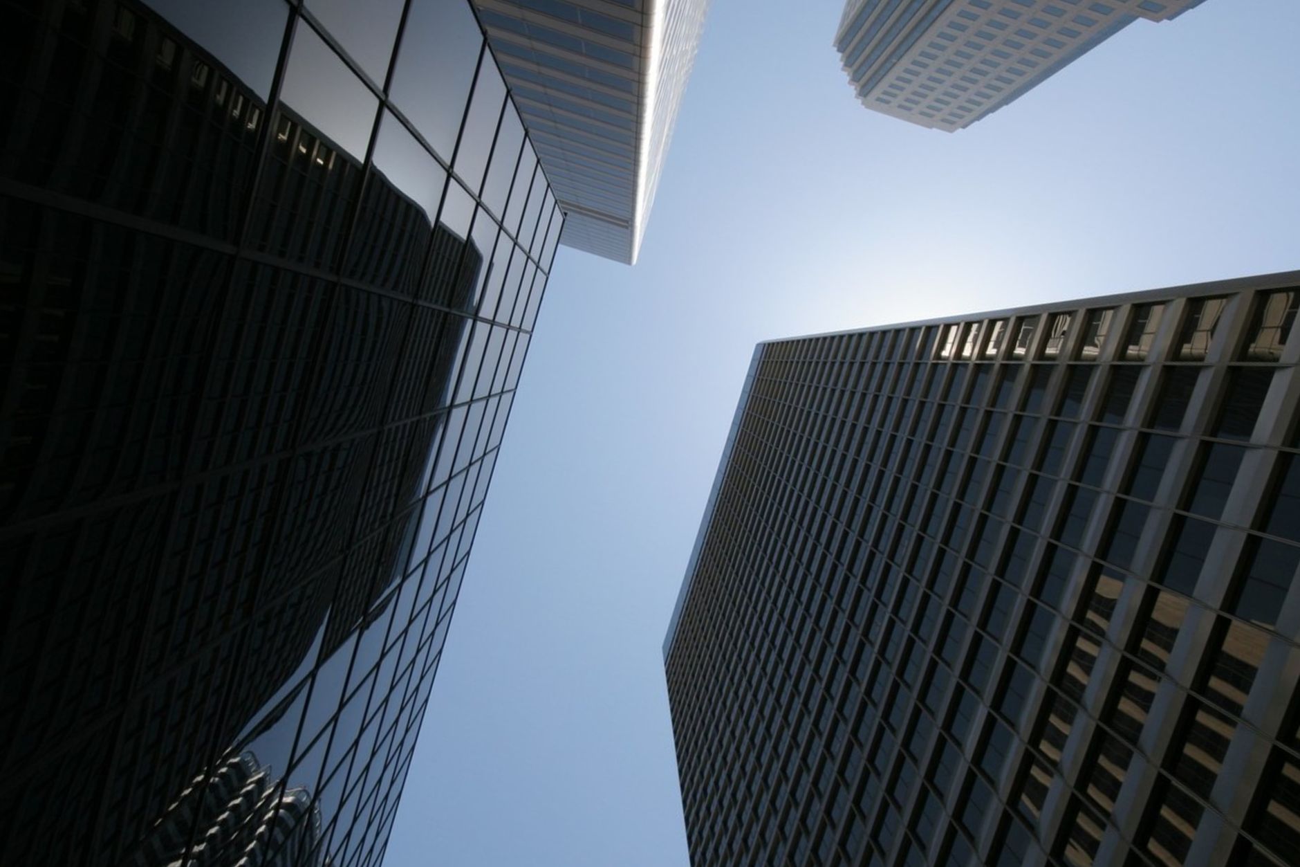 Low angle shot of skyscrapers against a clear blue sky emphasizing height and modern architecture.