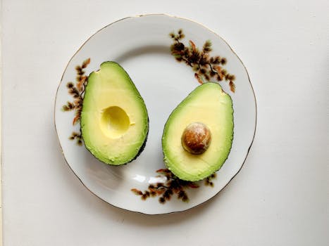 Close-up of sliced avocado on a decorative ceramic plate, showcasing fresh and nutritious fruit.