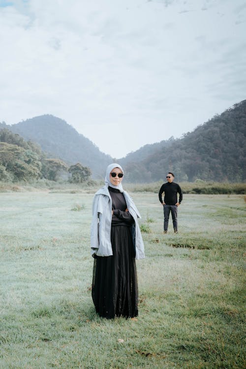 Man and Woman in Black Outfit Standing on the Grass Field 