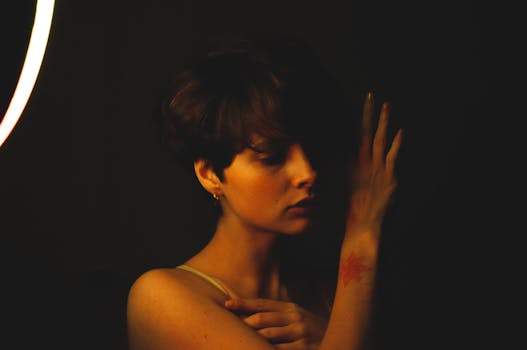Artistic portrait of woman with short hair and tattoo, moody lighting, side view.