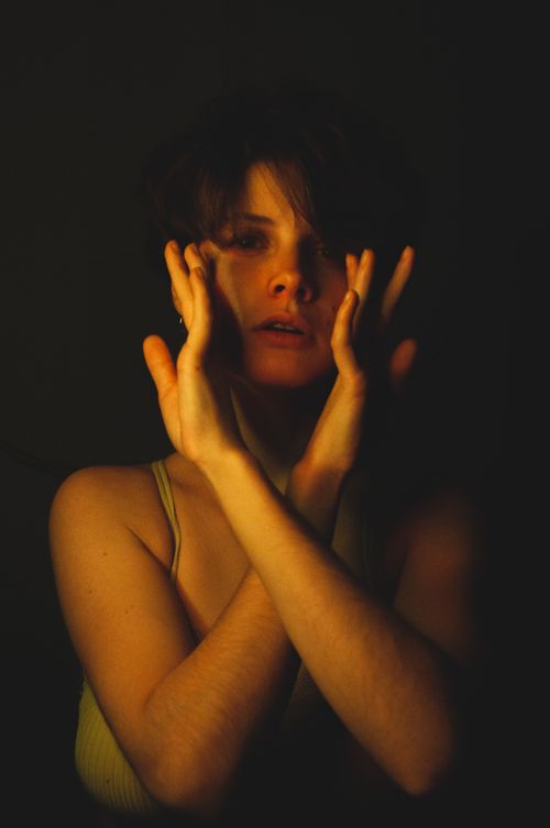 Free Moody studio portrait of a woman with crossed hands and dramatic shadows. Stock Photo