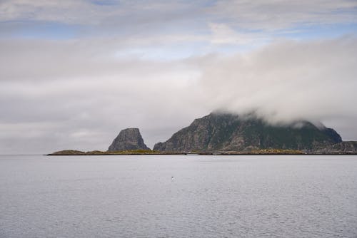 Free Rock Mountain in the Sea Covered with Low Clouds Stock Photo