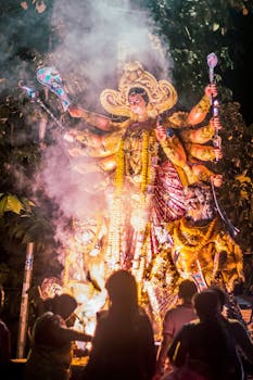 Vibrant depiction of a Hindu goddess statue during a nighttime Durga Puja festival with worshippers present.