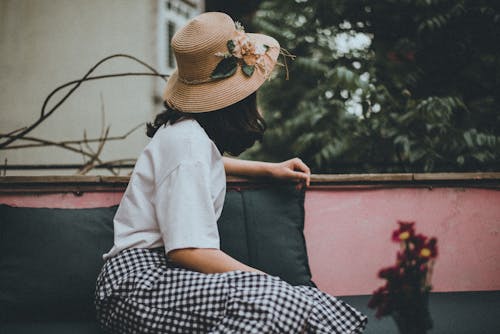 A woman wearing a floral hat enjoys leisure time on a Hanoi balcony, Vietnam.