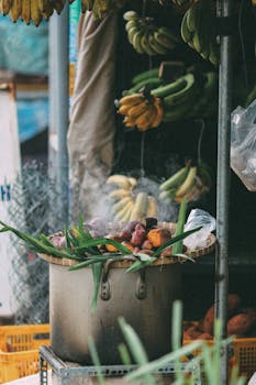A vibrant outdoor market stall showcasing bananas and cooking vegetables in a large pot.