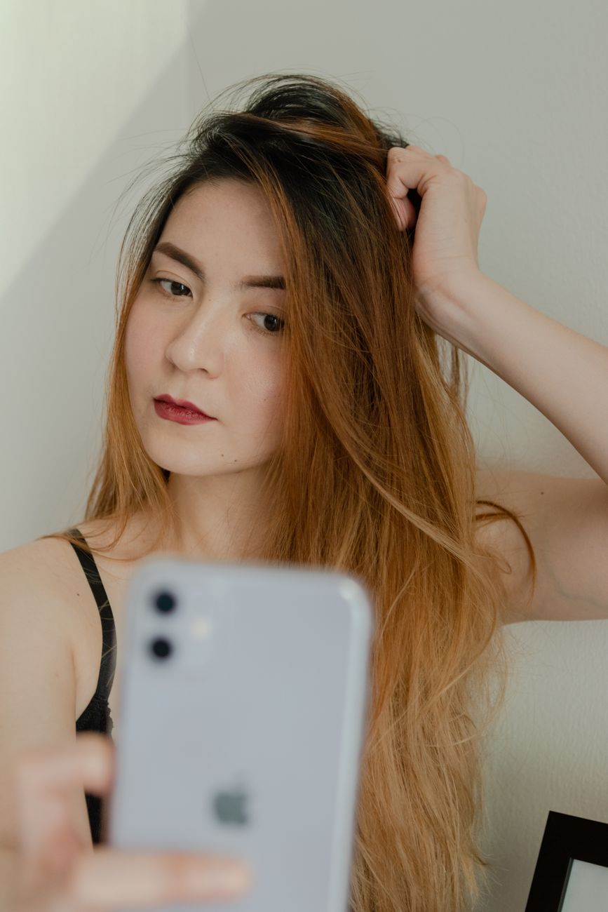 Beautiful woman with long hair taking a selfie indoors with a smartphone.