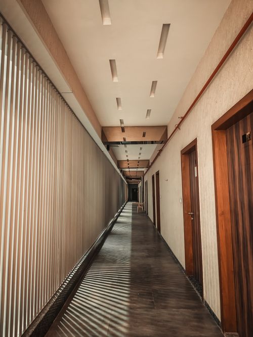 Free Warm-toned, empty corridor with wood doors in a Surat, India office building. Stock Photo