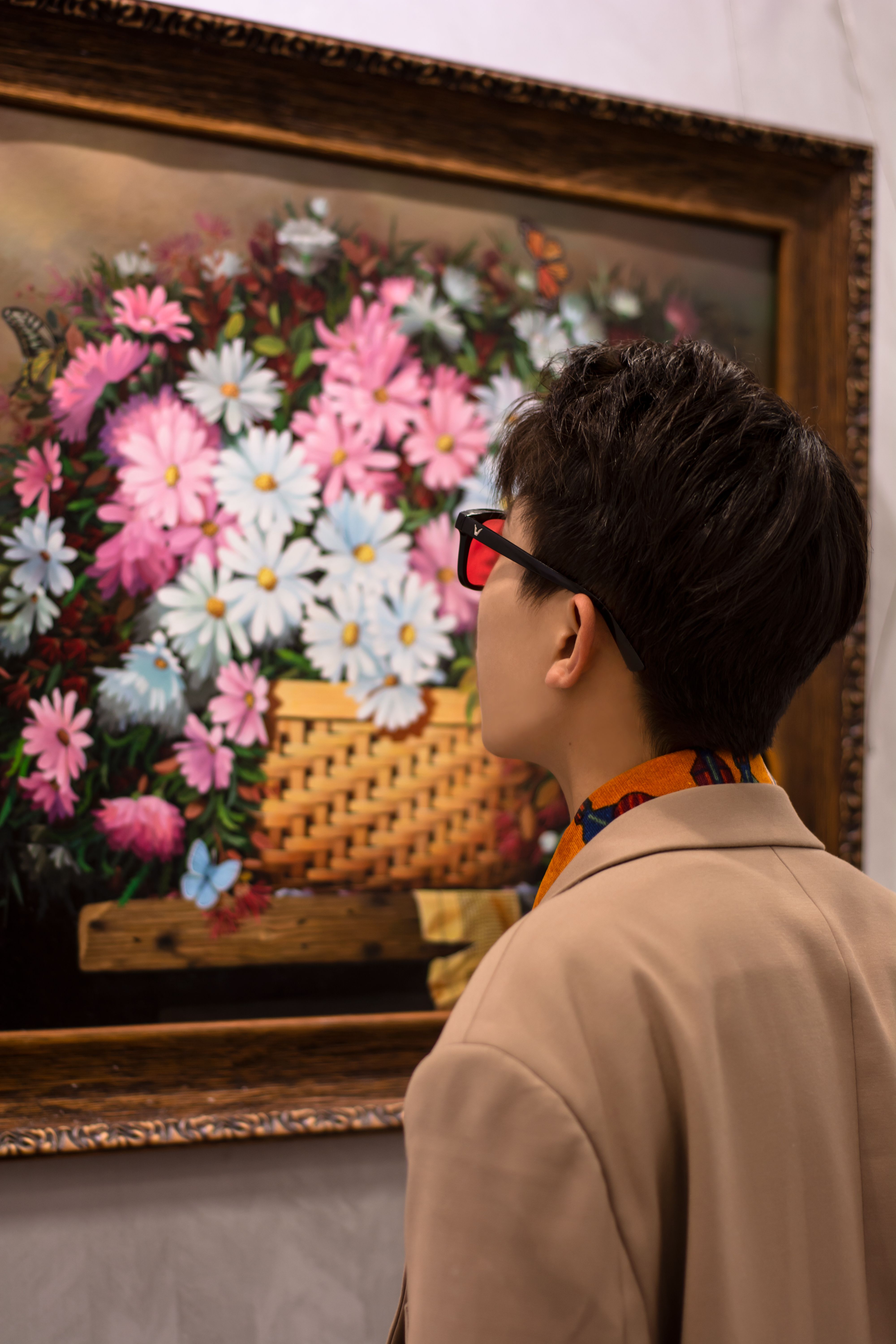 [ColoSach]-a-young-man-in-a-blazer-attentively-observing-a-colorful-floral-painting-in-a-gallery.