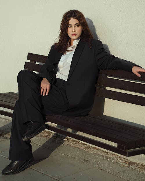 Woman in Black Suit Sitting on Brown Wooden Bench
