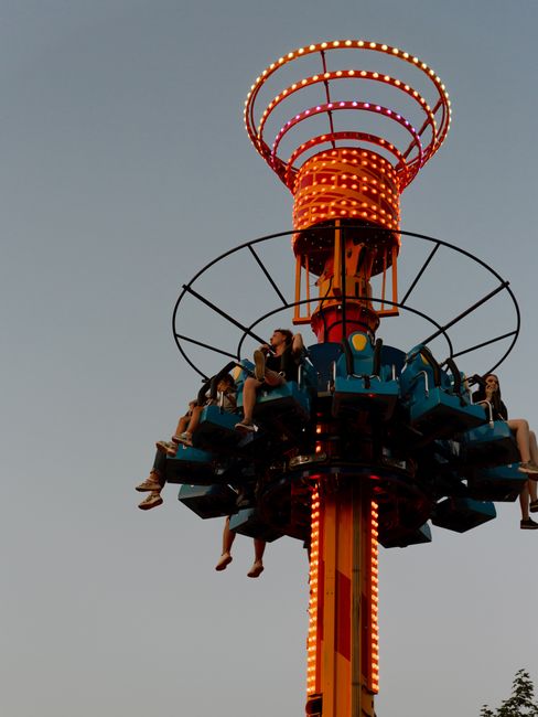 Thrilling amusement ride with people enjoying an exhilarating drop tower at sunset.