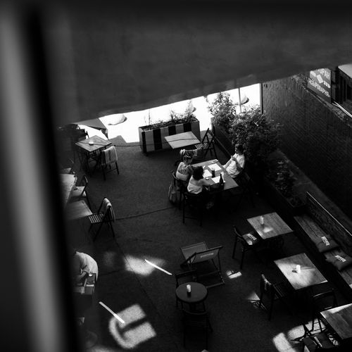Free Black and white aerial shot of people dining at an outdoor cafe with tables and chairs. Stock Photo