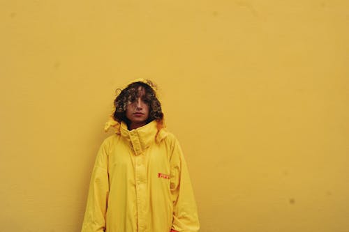 Woman Wearing Yellow Raincoat on Yellow Painted Wall