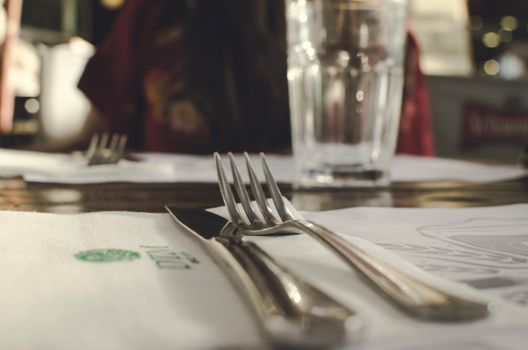 Close-up of a neat table setting with silverware and a glass in an indoor dining environment.