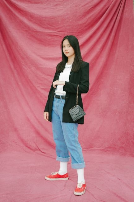 A fashionable woman poses confidently against a pink background, showcasing modern style.