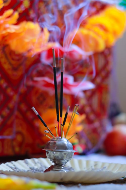 Free Incense sticks releasing smoke during an Indian ritual with vibrant decorations. Stock Photo