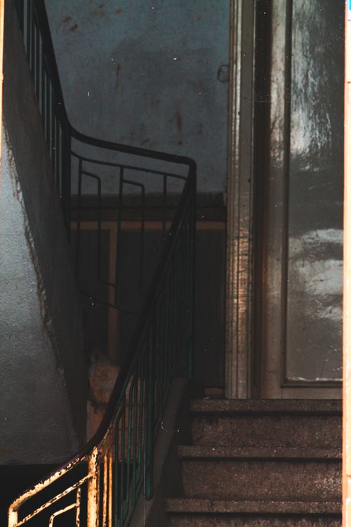 Free A dark and moody indoor stairwell with metal handrail and closed door. Stock Photo