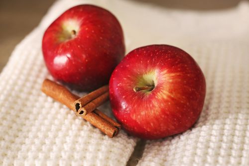 Free Fresh red apples and cinnamon sticks on a white textured cloth, perfect for illustrating autumn flavors. Stock Photo