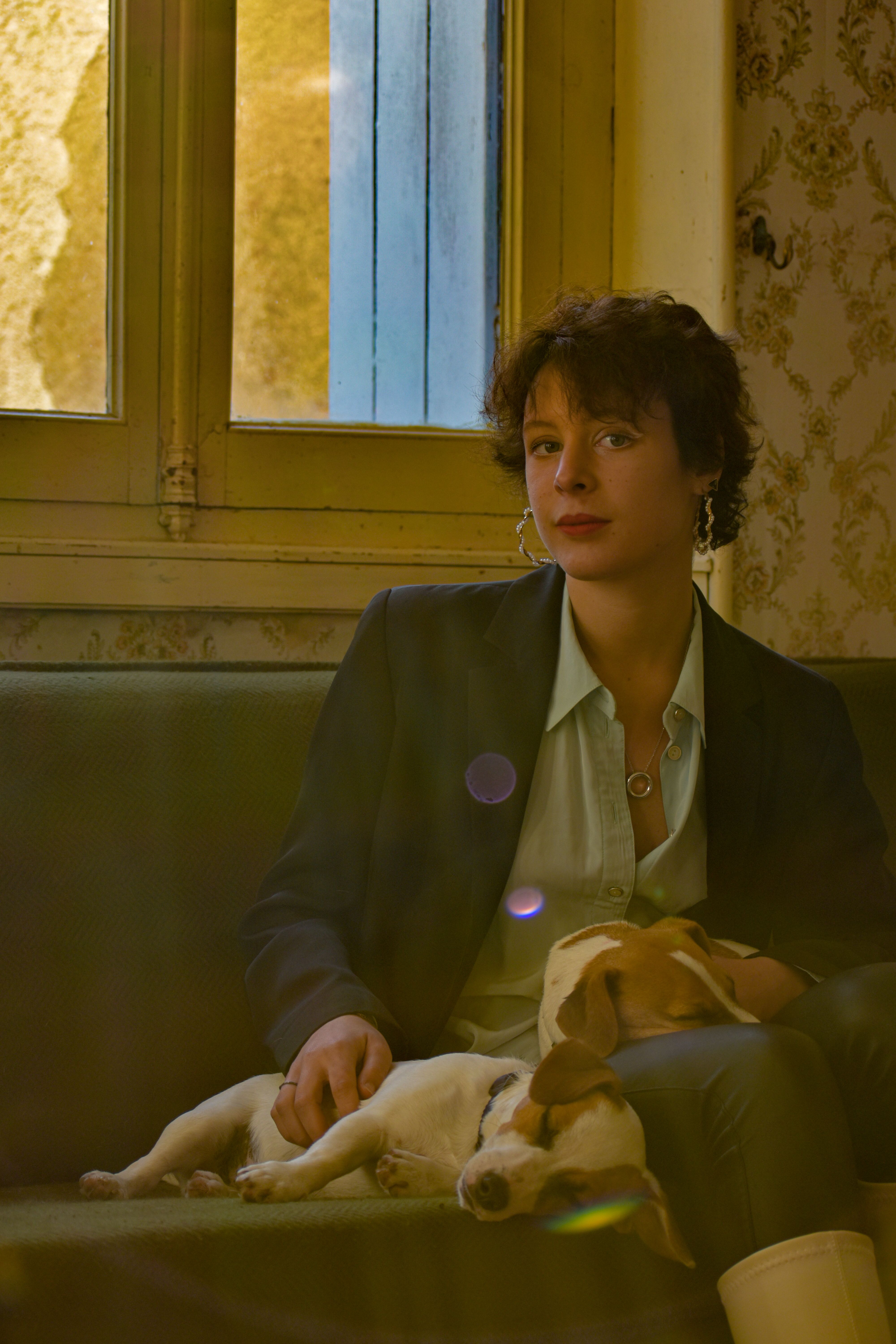 A young woman sitting indoors with a beagle on her lap, enjoying a peaceful moment in a Parisian setting.