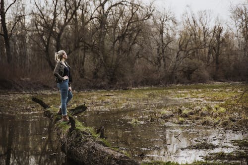 Mujer De Pie Sobre Driftwood Por Encima Del Cuerpo De Agua