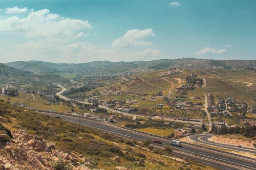 Free A picturesque aerial view showcasing a rural landscape with winding roads and hills under a clear blue sky. Stock Photo