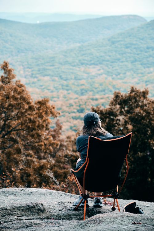 Free Person enjoying a peaceful moment on a mountain top overlooking a scenic forest view. Stock Photo