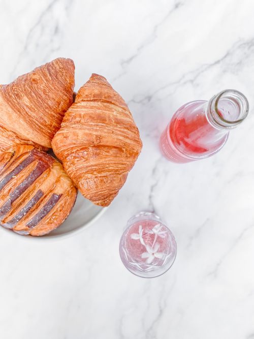 Free Top view of freshly baked croissants with a refreshing sparkling rose drink on marble. Stock Photo