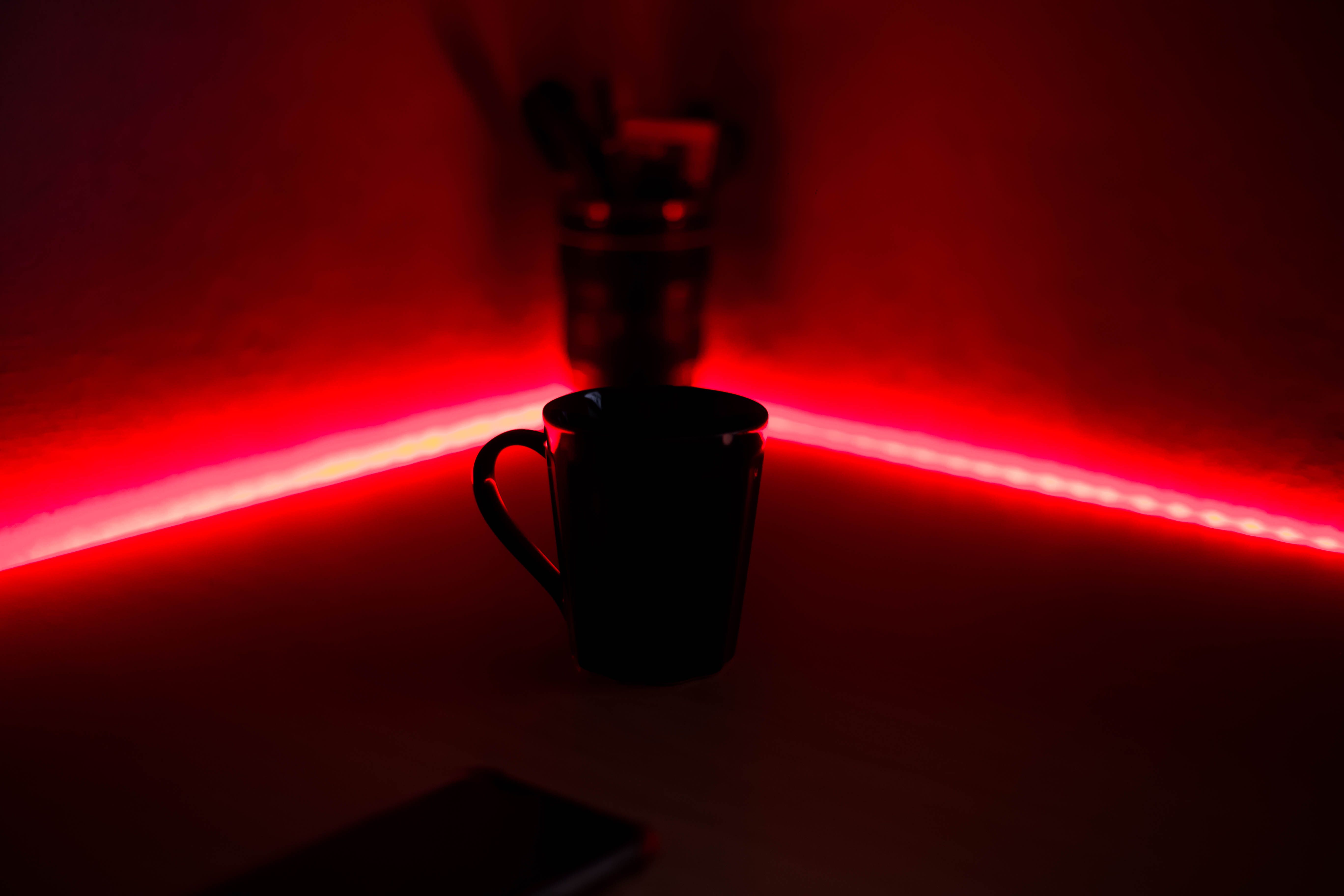 A black cup illuminated by red LED lights in a dark indoor setting, offering a moody atmosphere.