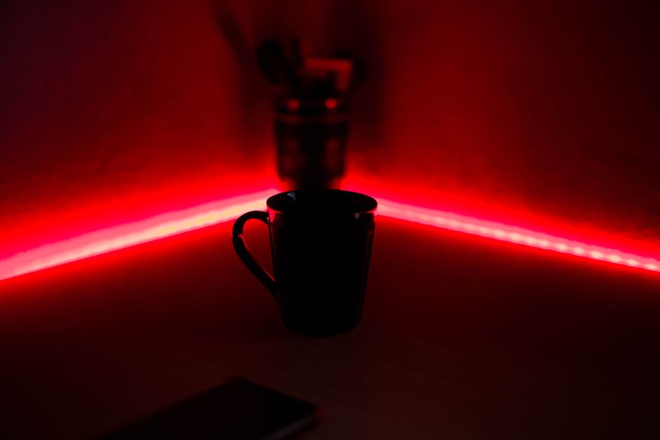 A black cup illuminated by red LED lights in a dark indoor setting, offering a moody atmosphere.