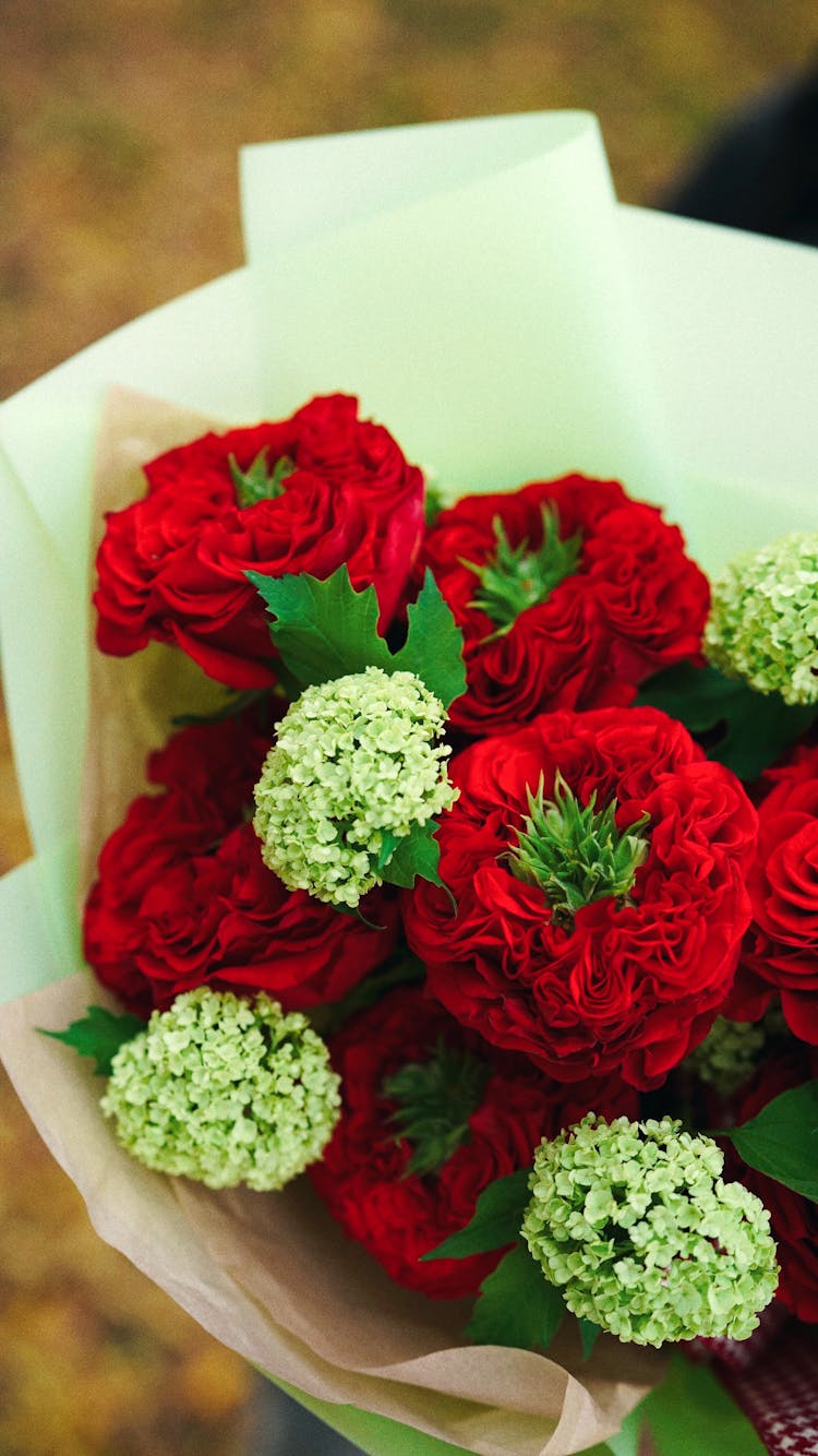 Bunch Of Red And White Flowers With Ribbon Wrapped In Decorative Paper