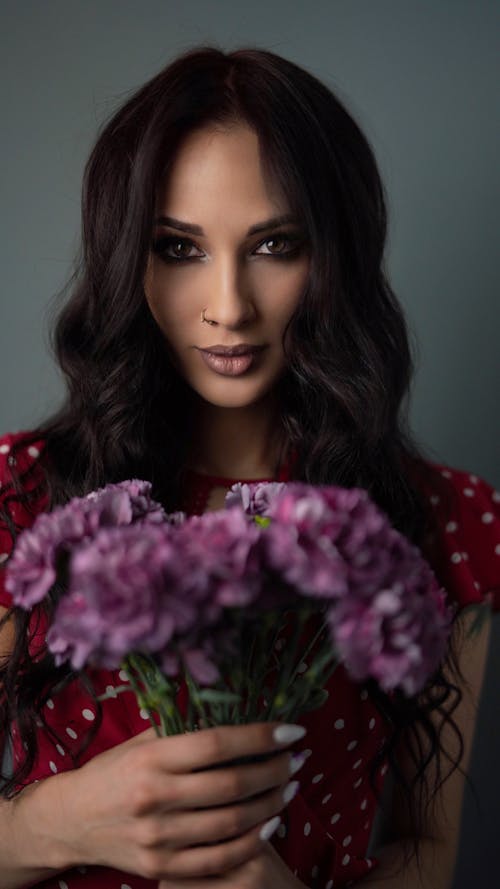 Free Woman in Red and White Polka Dot Shirt Holding Purple Flowers Stock Photo