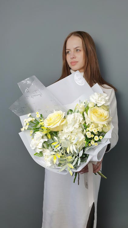 Free A Beautiful Woman Holding a Bouquet of White Flowers Stock Photo