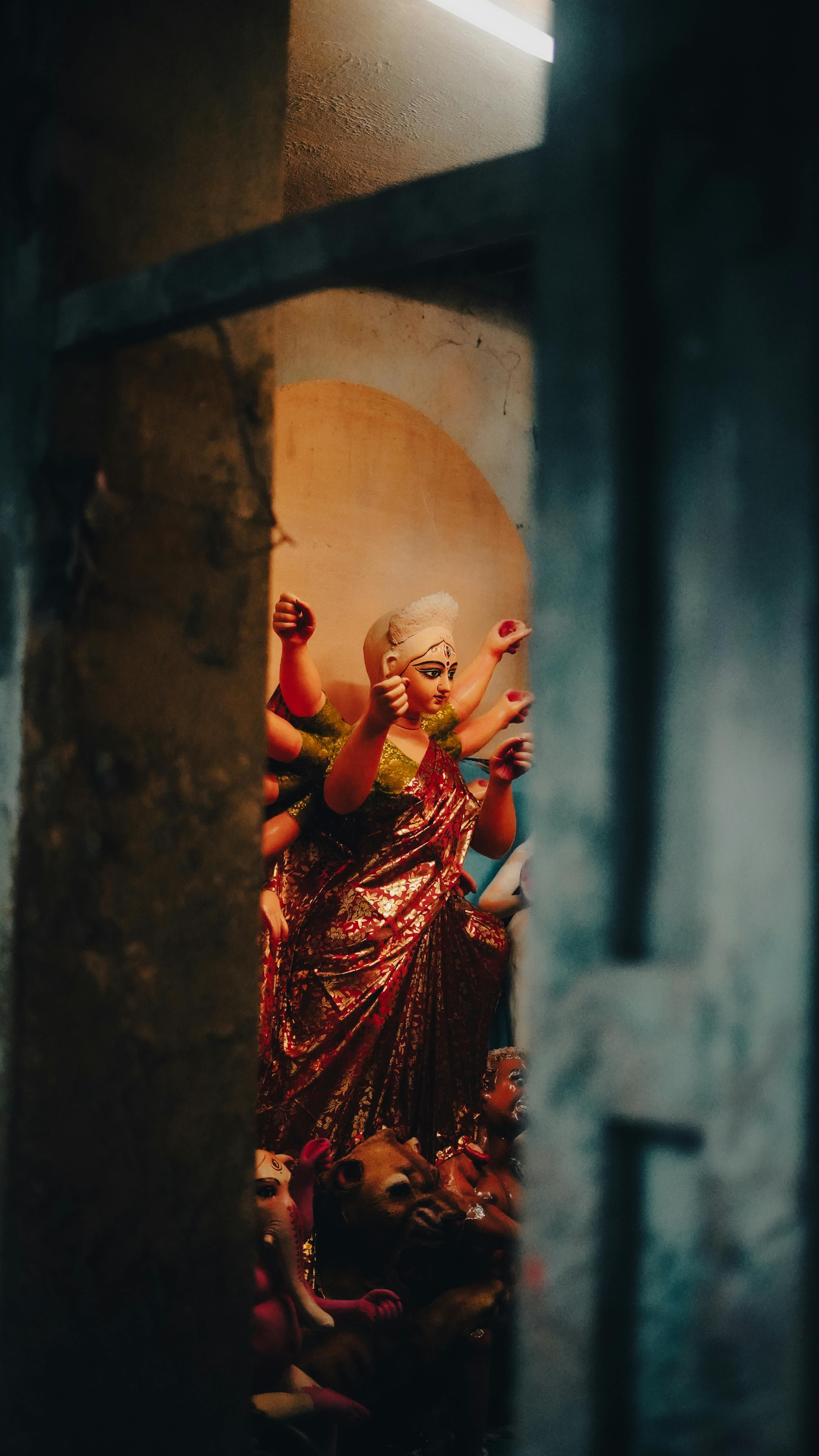 View of a Hindu goddess statue captured through a rustic door, highlighting cultural and religious artistry.