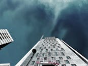 现代摩天大楼的玻璃幕墙与戏剧性的云层，构成了一幅低角度的视图