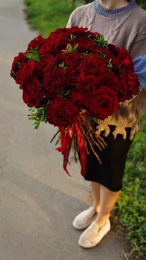 Free Close Up Photo of Woman Holding Red Flowers Stock Photo