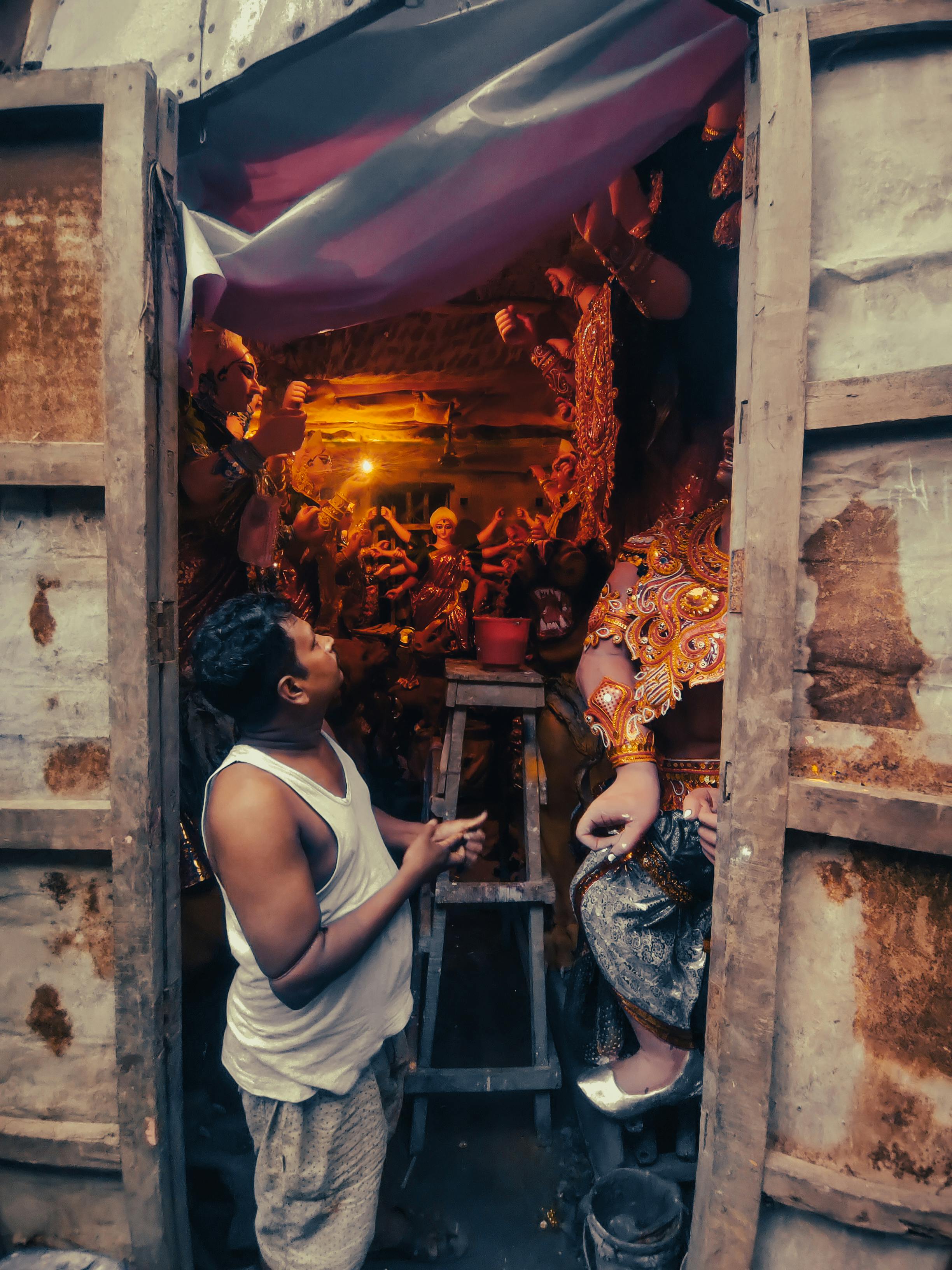 A man working on traditional Durga idol craftsmanship in a Kolkata workshop, captured in a rustic setting.