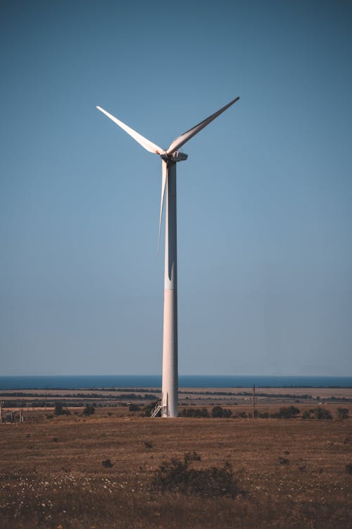 White Wind Turbine on Brown Field Under Blue Sky